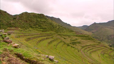 Panning shot of terraced hills looking down at a town in Peru