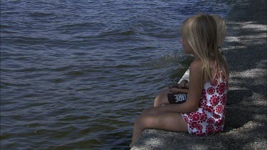 A boy and a girl siiting by the water.