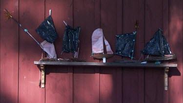 A shelf with toy wooden boats against a red wall in Sweden