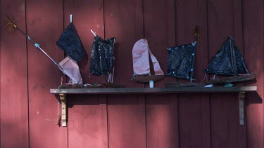 A shelf with toy wooden boats against a red wall in Sweden