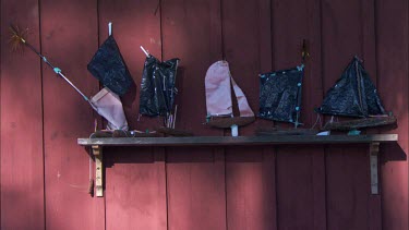 A shelf with toy wooden boats against a red wall in Sweden