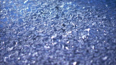 Close up of ice formed on a blue car.