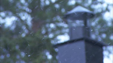 Snow falling with chimney in the background