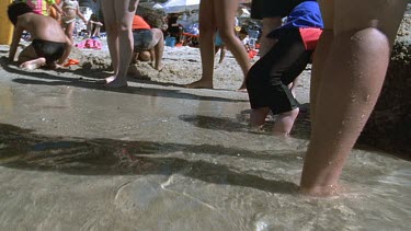 POV of penguin coming onto beach moving low through beach crowded with holiday makers