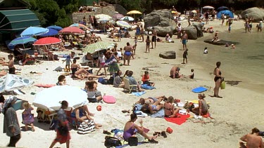 Holidaymakers on a crowded beach: umbrellas, swimming etc