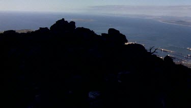 Reveal from top of Table Mountain to view of Cape Town city and harbour below.