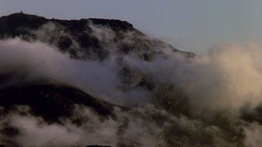 Wispy clouds blowing in towards mountain