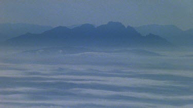 Mountain peaks stick out above low lying cloud.