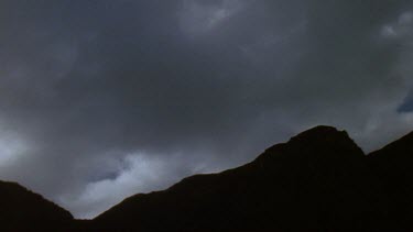 Clouds blowing over top of mountain.