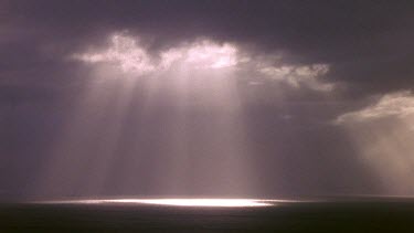 Shaft of light piercing storm clouds travels over sea