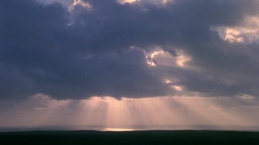 Shaft of light piercing storm clouds travels over sea