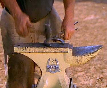 Farrier with horse-shoe. Fire and anvil.