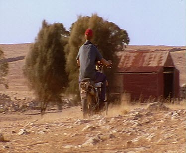 Off-road motorbike drives into distance.