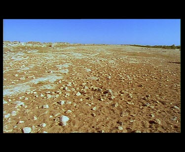 And tilt up. Very dry desert barren land. Sand and rock. Stone walls.