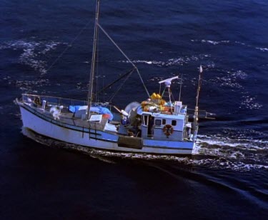 Fishing boat going out to sea. Tasmania West Coast Light House on island