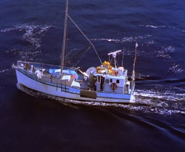 Fishing boat going out to sea. Tasmania West Coast Light House on island