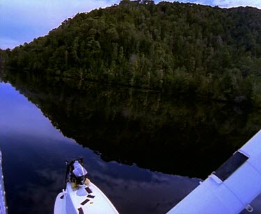 Franklin River. Reflections of clouds on still water. Flying down the rivers meander. Thick rainforest on banks of river.