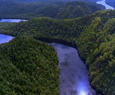 Franklin River. Reflections of clouds on still water. Flying down the rivers meander. Thick rainforest on banks of river.