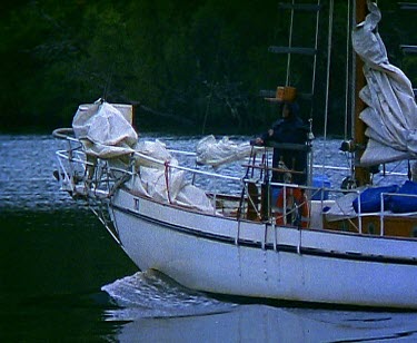 Yacht cruising up still river rainforest on banks.