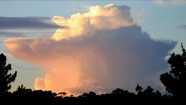 A spectular cloud formation expands as the sun sets to darkness. Comulo-nimbus cloud. Rain cloud.