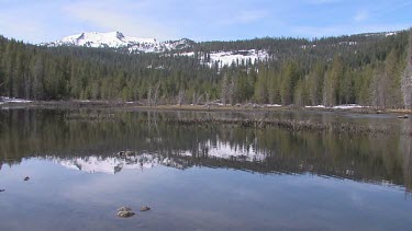 Rippling lake in alpine setting with reflection of snow peaked mountain