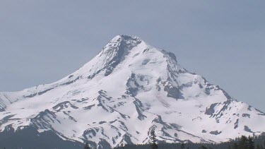Mountain with snowy peak, blue sky and forest