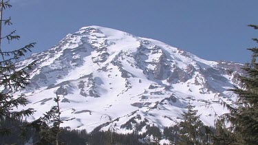 Mountain with snowy peak, blue sky and forest