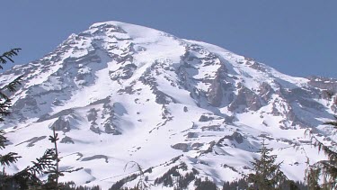 Mountain with snowy peak, blue sky and forest