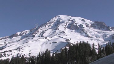 Mountain with snowy peak, blue sky and forest