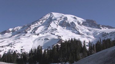 Mountain with snowy peak, blue sky and forest