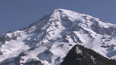 Mountain with snowy peak, blue sky and forest