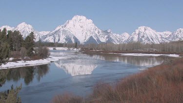 Mountain with snowy peaks and blue sky reflected in lake