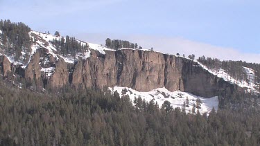 Snow topped mountain, cliff and forest