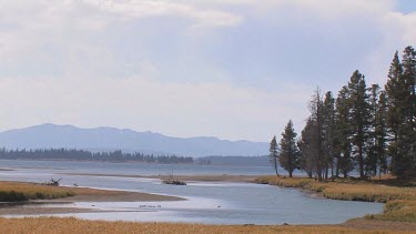 Large pristine lake, rocky mountains, forest, and big sky