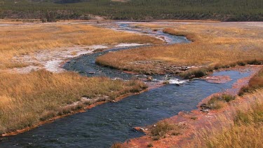 Colorful blue stream flows out into a high valley of the Rocky Mountains