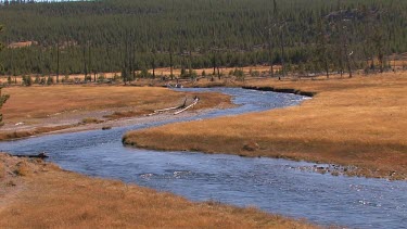 Colorful blue river flows out into a high valley of the Rocky Mountains