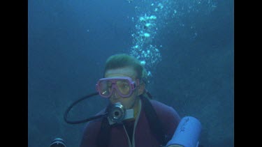 Valerie looking around, swimming in front of rock