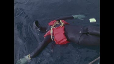 man pulls out dummy from water and inspects for shark bites