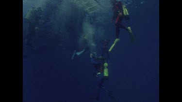 divers break surface and sit on boat platform