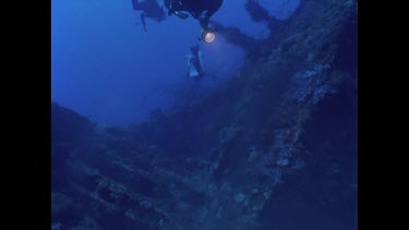 divers swim around Yongala wreck