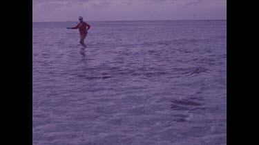 Valerie walking through shallow water, black tip shark swims