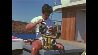 Henri Bource with 16 mm camera and underwater housing. Preparing camera for filming underwater.