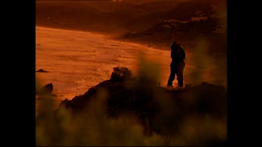 Couple kissing at sunset with ocean in background