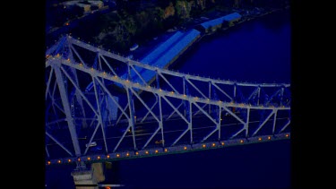 Night. Structure of Storey Bridge pull back to reveal river and city in gentle yellow light.