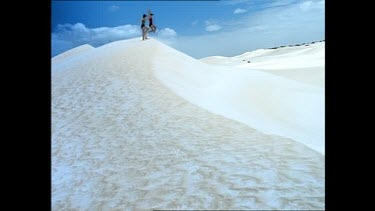 Two people playing on a very white sand dune