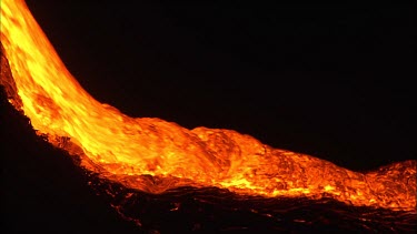 Active volcano. Lava flow. River of lava pouring down slope. Night.