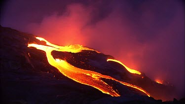 Volcano. Magma coming to surface through fissure. When magma reaches the surface it is called lava. The lava flows down a channel straight into the sea. Waves crashing at base of volcano. Steam rising...