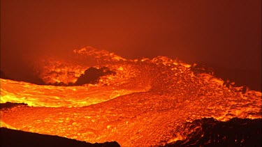 Volcano. Lava flowing quickly into the sea. Waves crashing and steam.