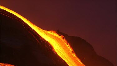 Volcano. Lava flowing quickly into the sea. Waves crashing, throwing debris into the air. steam.