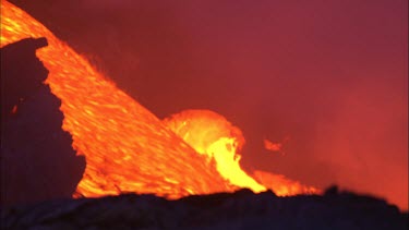 Volcano erupting night. WAves crashing splashing and steam.